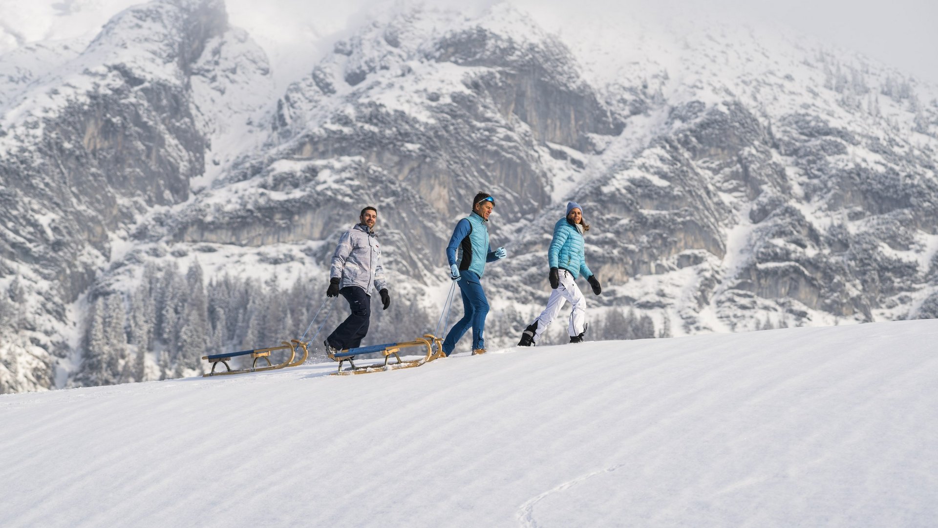 Drei Menschenbeim Rodeln im Winterurlaub in Tirol